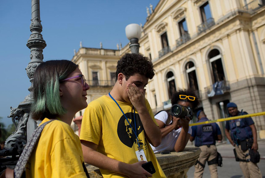 National Museum employees cry as they look at the burned building on Monday (September 3.) AP PHOTO/SILVIA IZQUIERDO